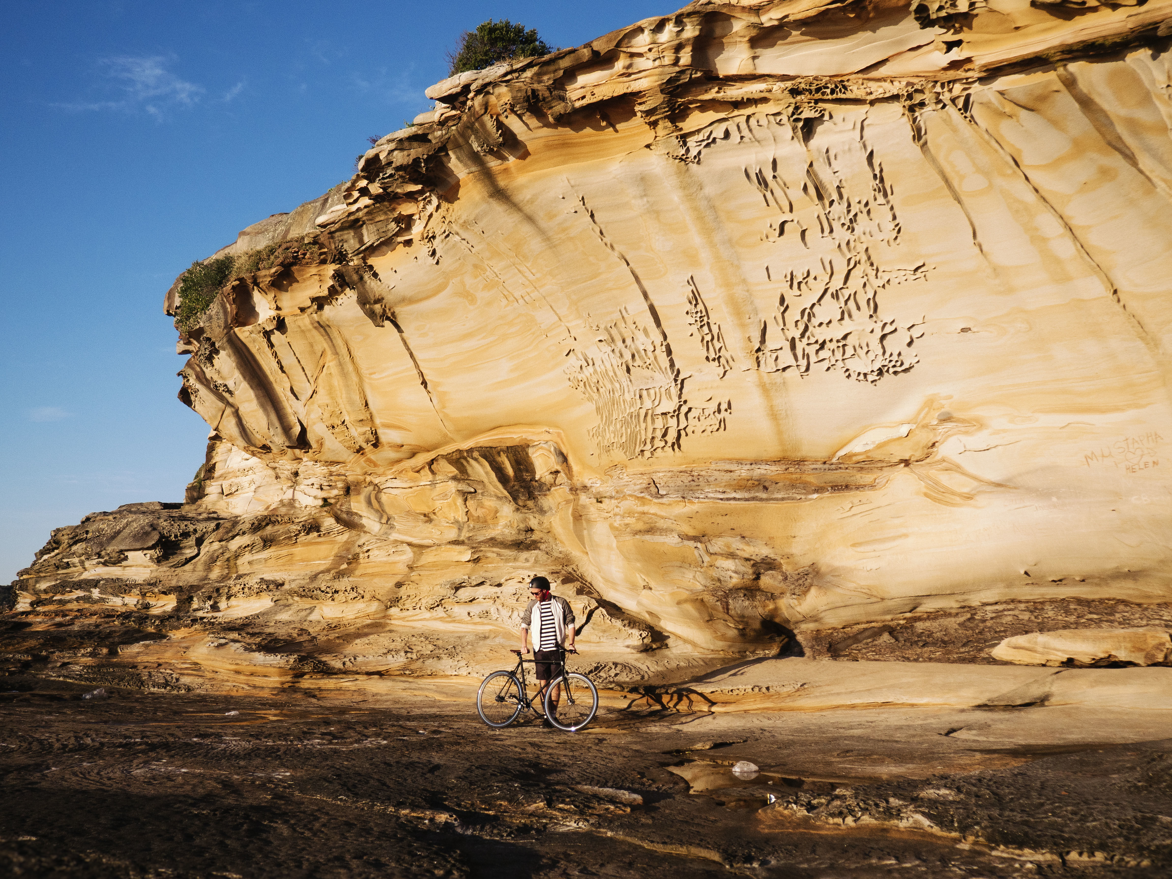 Cyclist in front of rock wall, Kamay Botany Bay National Park. Photo: Nick Alfred