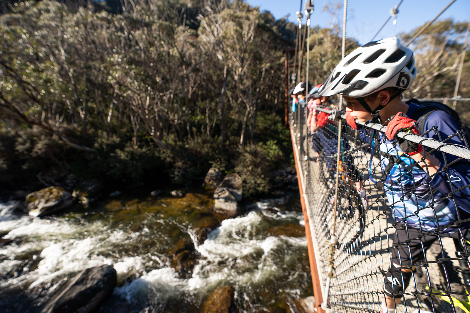 People peering over the bridge to look at the Thredbo Valley river below, Kosciuszko National Park. Photo credit: Rob Mulally/DPIE