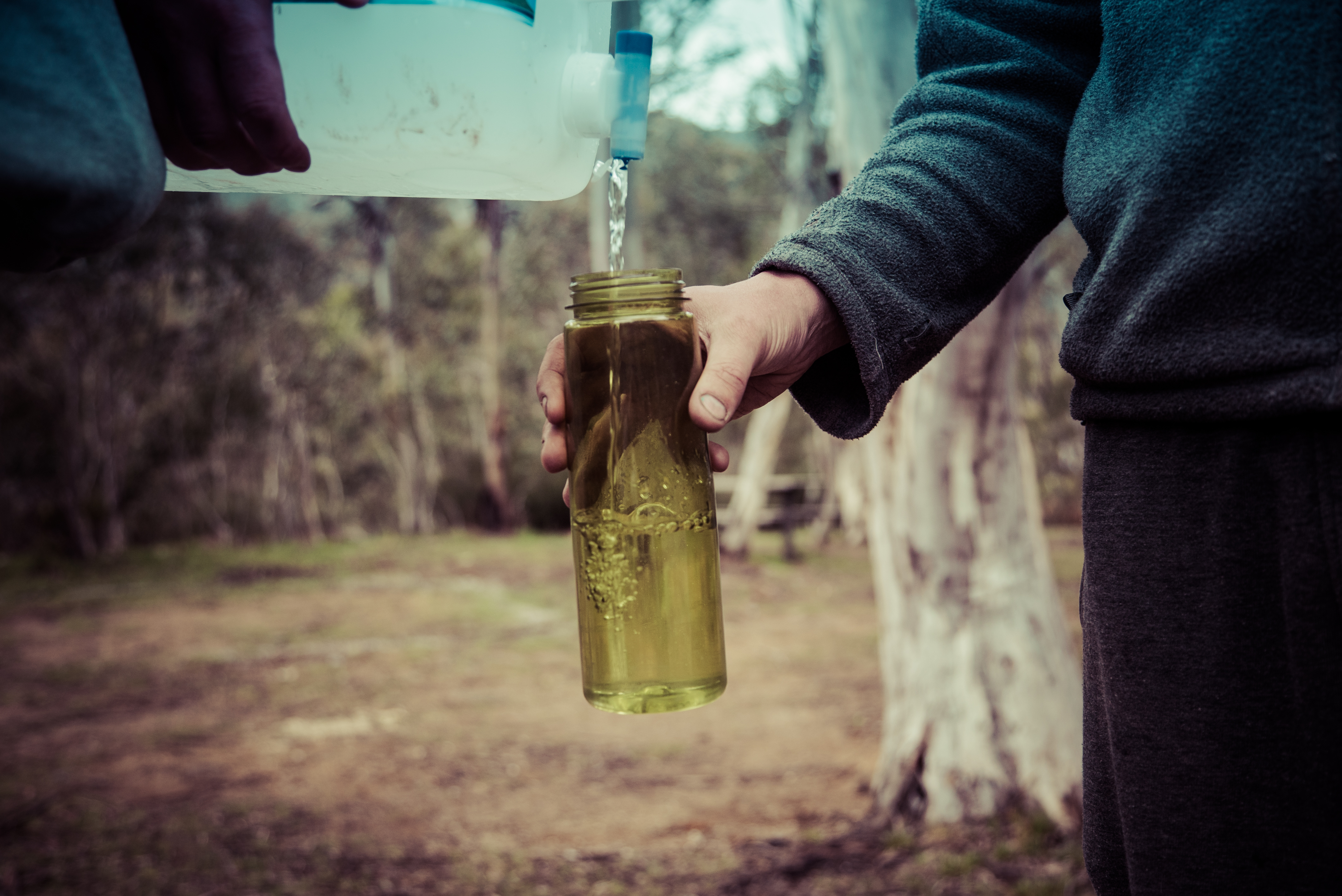 People filling a water bottle in Kosciuszko National Park. Photo: Person admiring view of Snowy Mountains, Kosciuszko National Park. Photo: Daniel Parsons/DPIE