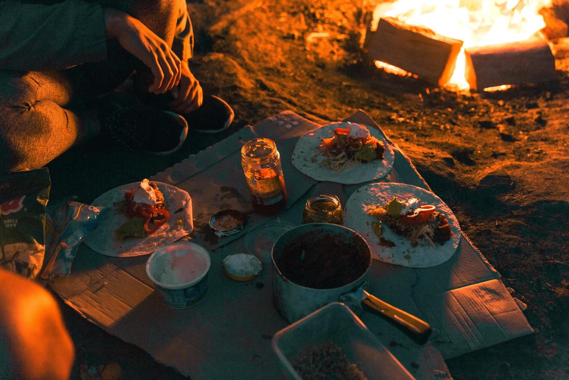 Group of people eating around a campfire at The Basin campground in Ku-ring-gai Chase National Park. Photo credit: Tim Clark/DPIE