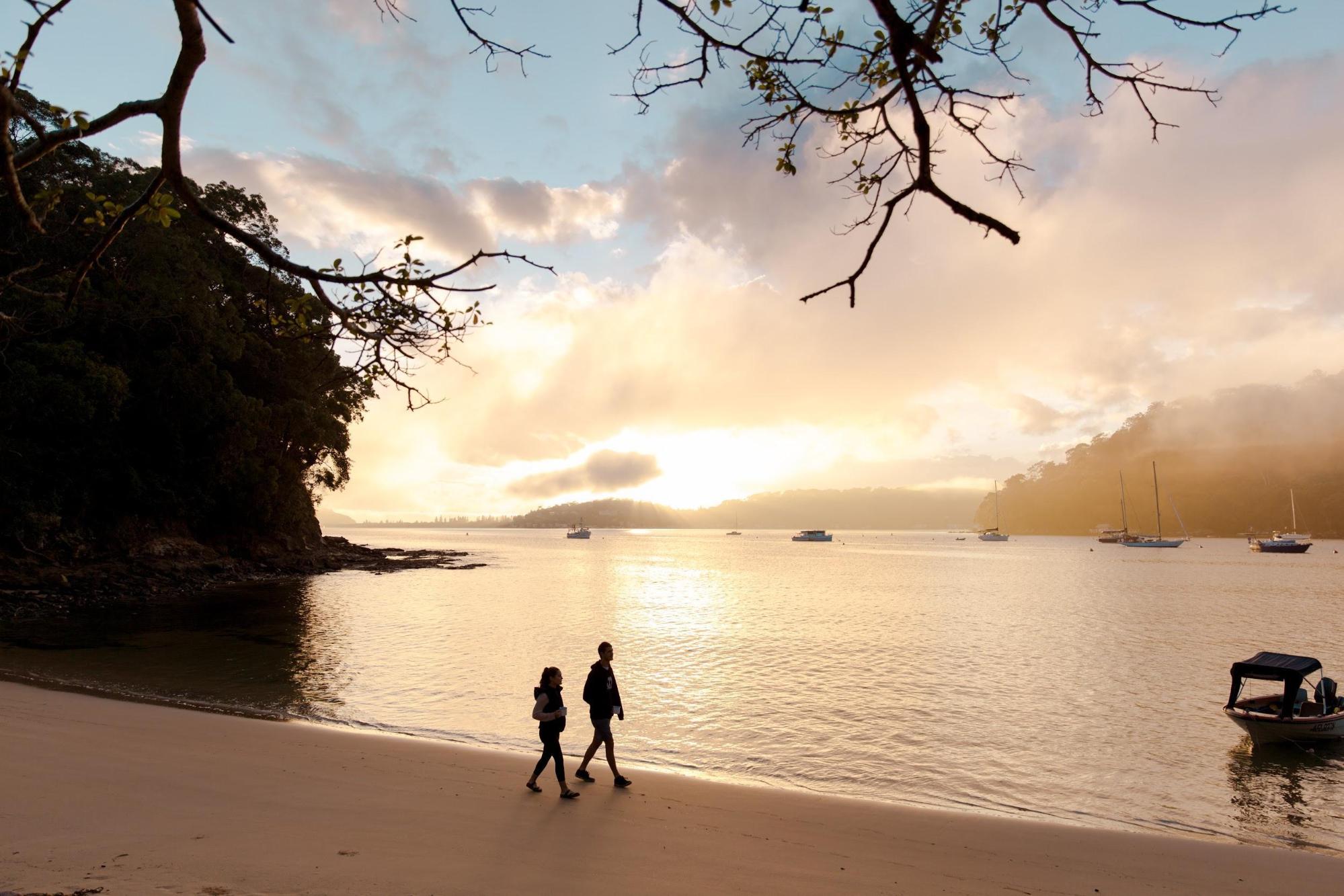 Two people walking along Resolute Beach in Ku-ring-gai Chase National Park. Photo credit: Tim Clark/DPIE