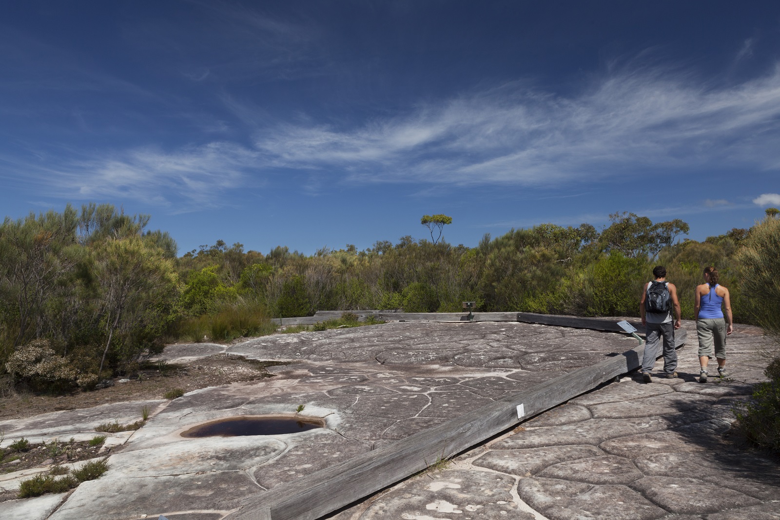 Two people walking past Basin Aboriginal art site in Ku-ring-gai Chase National Park. Photo credit: David Finnegan/DPIE