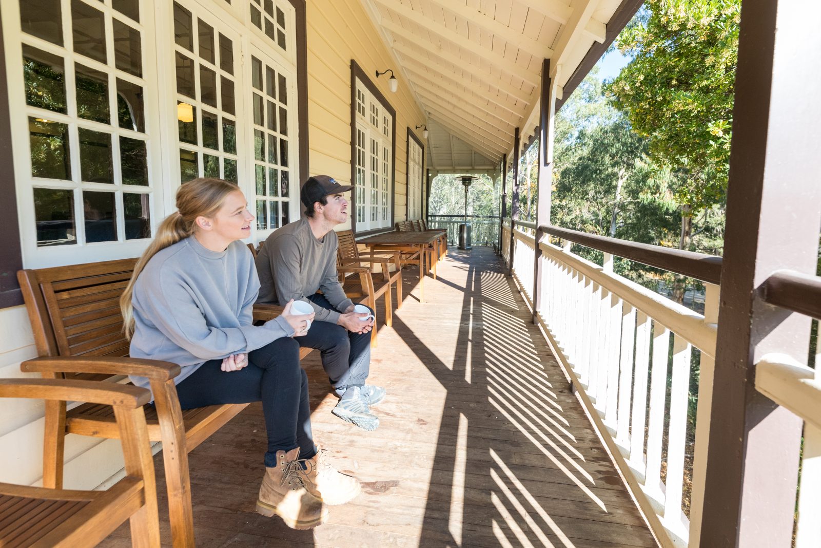 Two people sitting outside Yarrangobilly Caves House 1917 section in Kosciuszko National Park. Photo credit: Boen Ferguson/DPIE