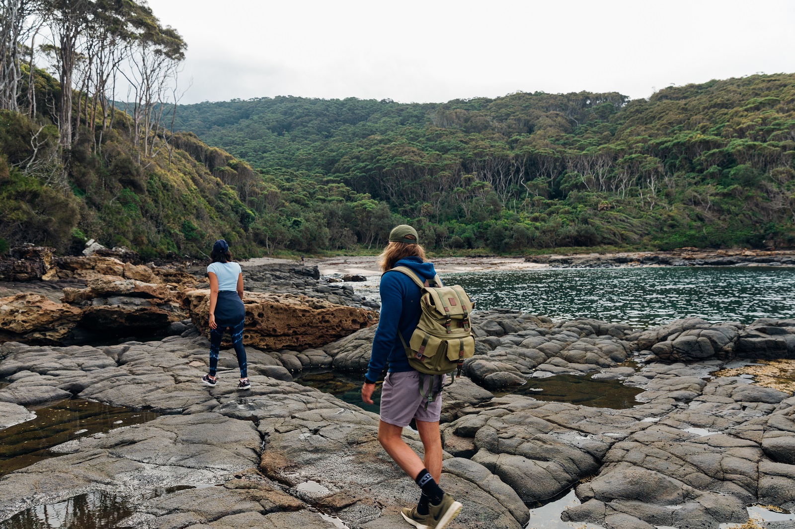 A woman and a man walking across the rocks at Pretty Beach. Photo credit: Melissa Findley/DPIE