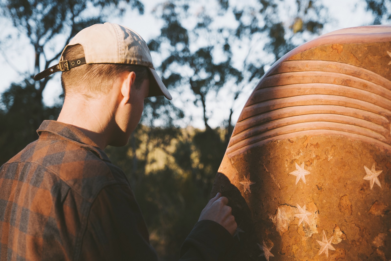 A man with a close up look of a sculpture in the Sculptures in the Scrub walking track. Photo: Harrison Candlin/DCCEEW © Harrison Candlin