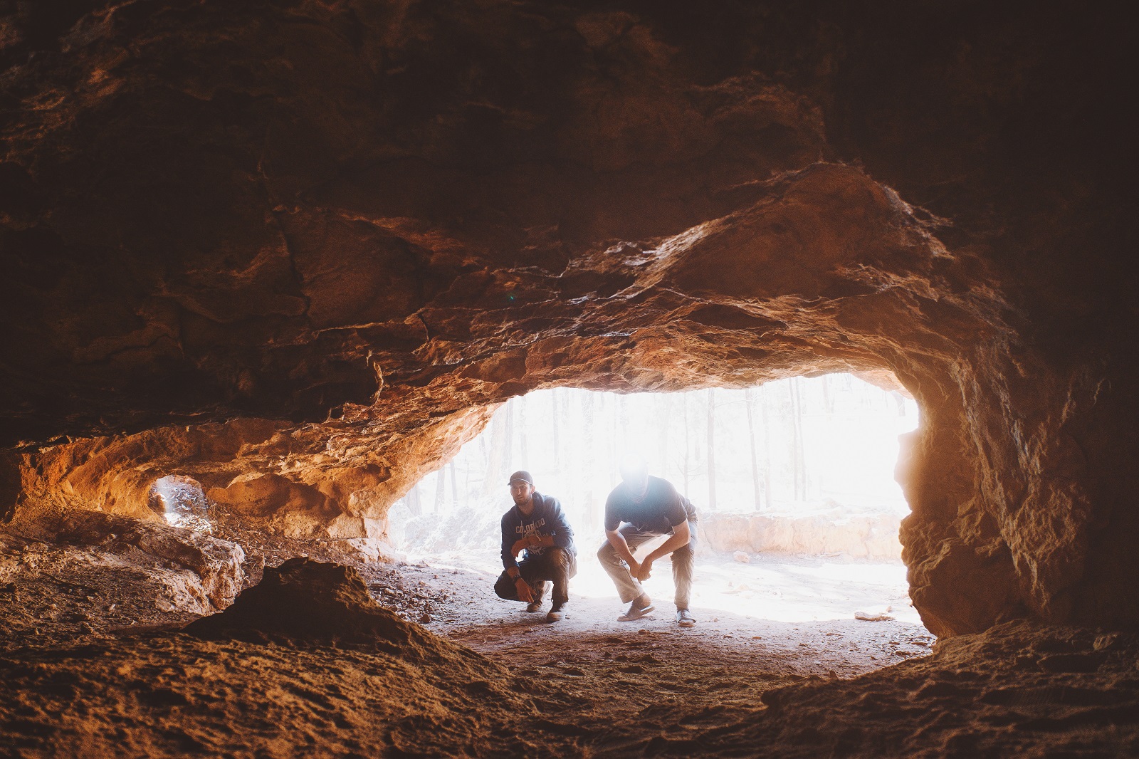 Two men crouching to look in the Salt Caves at the Pilliga in Timmallallie National Park. Photo: Harrison Candlin/DCCEEW © Harrison Candlin