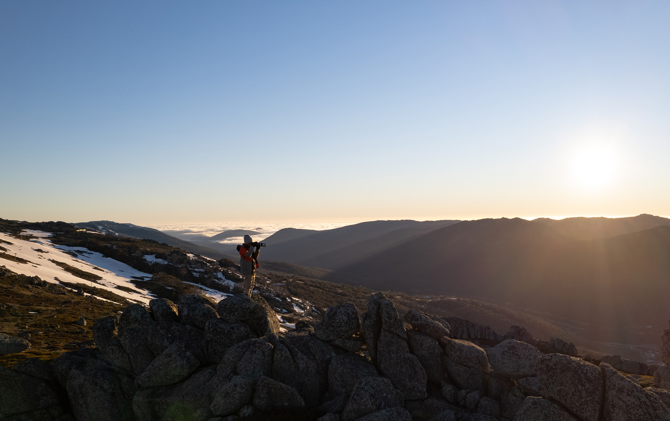 A man taking a photo of the sunset in Kosciuszko National Park. Photo credit: Jimmy Mellowes / DPE