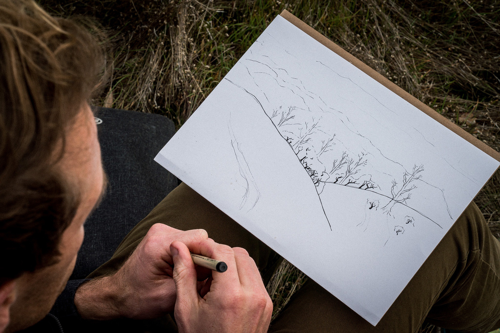 A male with a pen in his hand sketching. Photo: Pexels/Eli Zaturanski