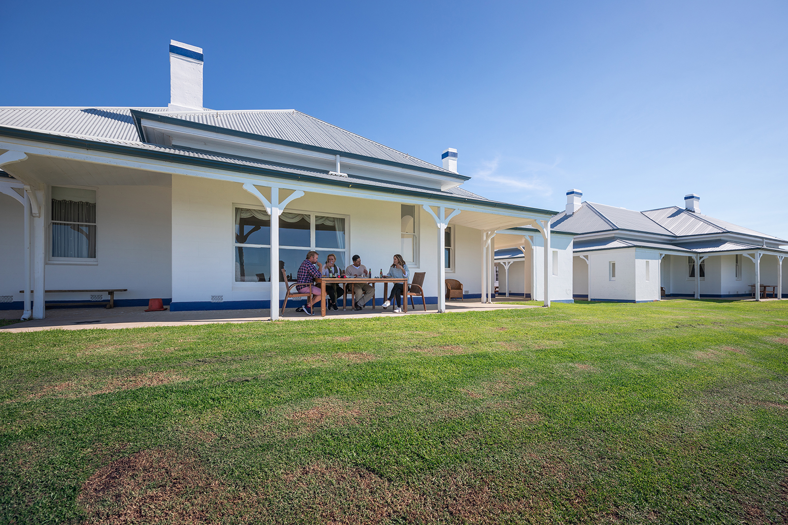 Four people having lunch outside the Head Lighthouse Keeper's Cottage, Montague Island Nature Reserve. Photo credit: Daniel Tran/DPIE