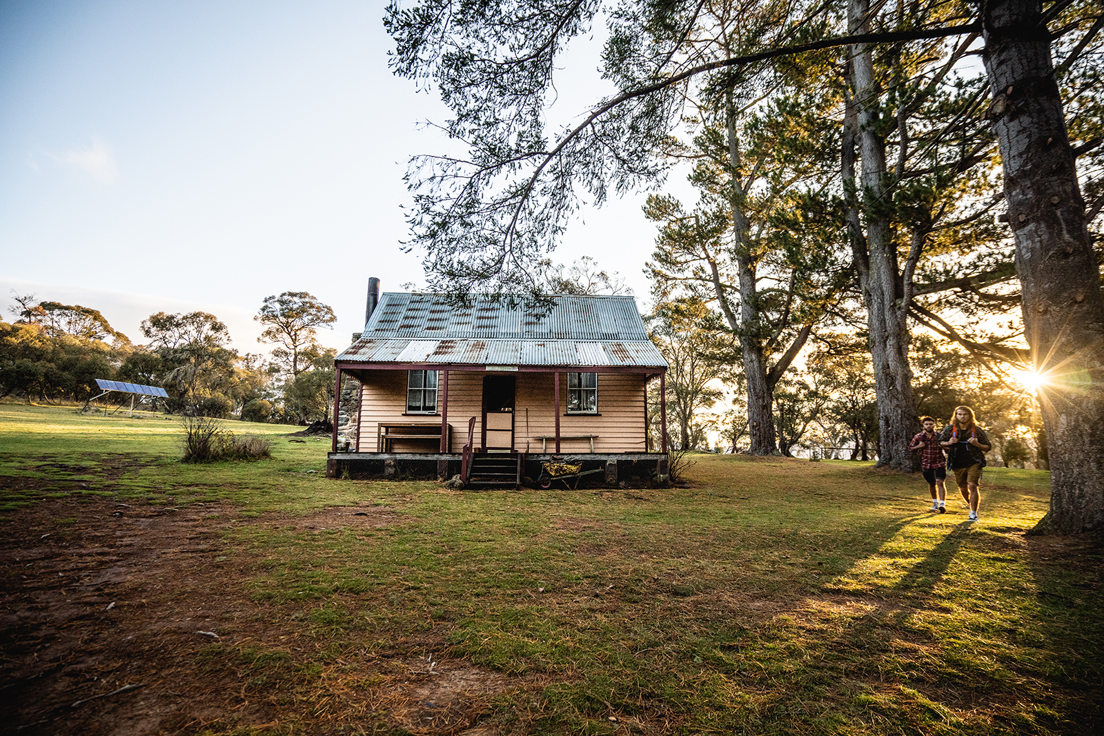 Two people walking past Daffodil cottage in Kosciuszko National Park. Photo credit: Rob Mulally/DPIE