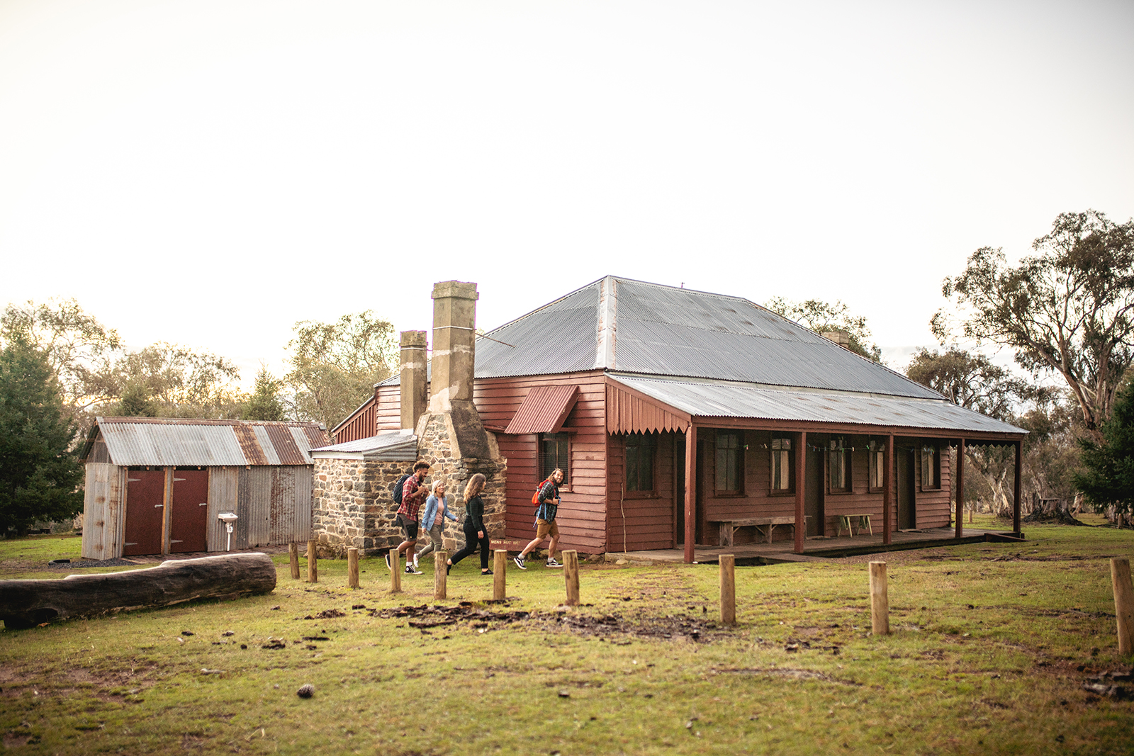Four people walking past The Pines Cottage in Kosciuszko National Park. Photo credit: Rob Mulally/DPIE