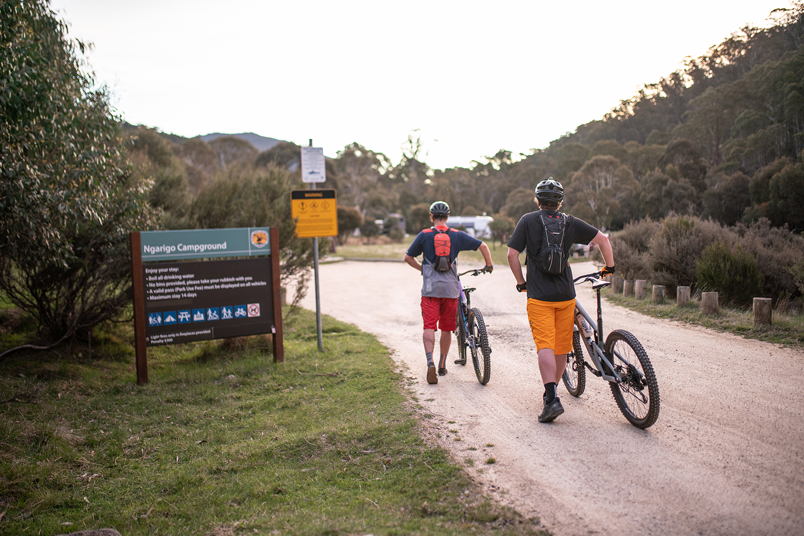 Two people walking with their bikes into Ngarigo campground, Thredbo-Perisher area in Kosciuszko National Park. Photo credit: Rob Mulally/DPIE