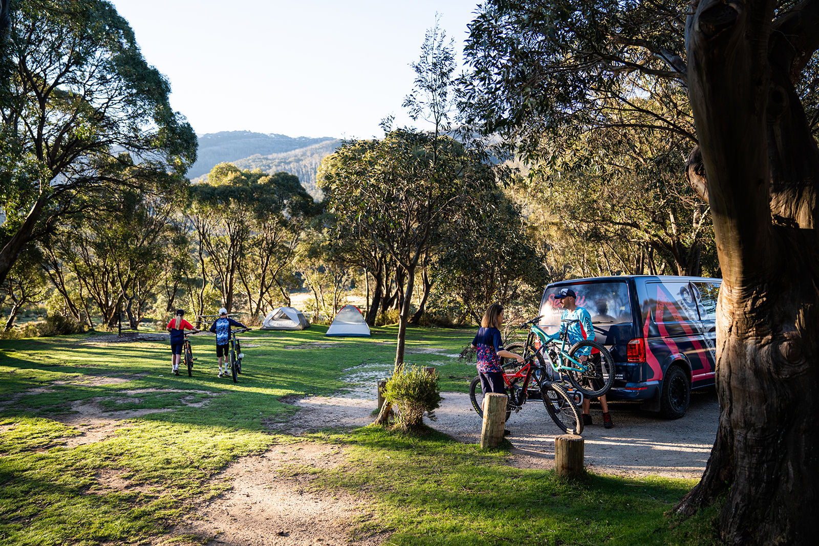 Four people walking their bikes to their tents in Thredbo Diggings campground, Thredbo-Perisher area in Kosciuszko National Park. Photo credit: Rob Mulally/DPIE