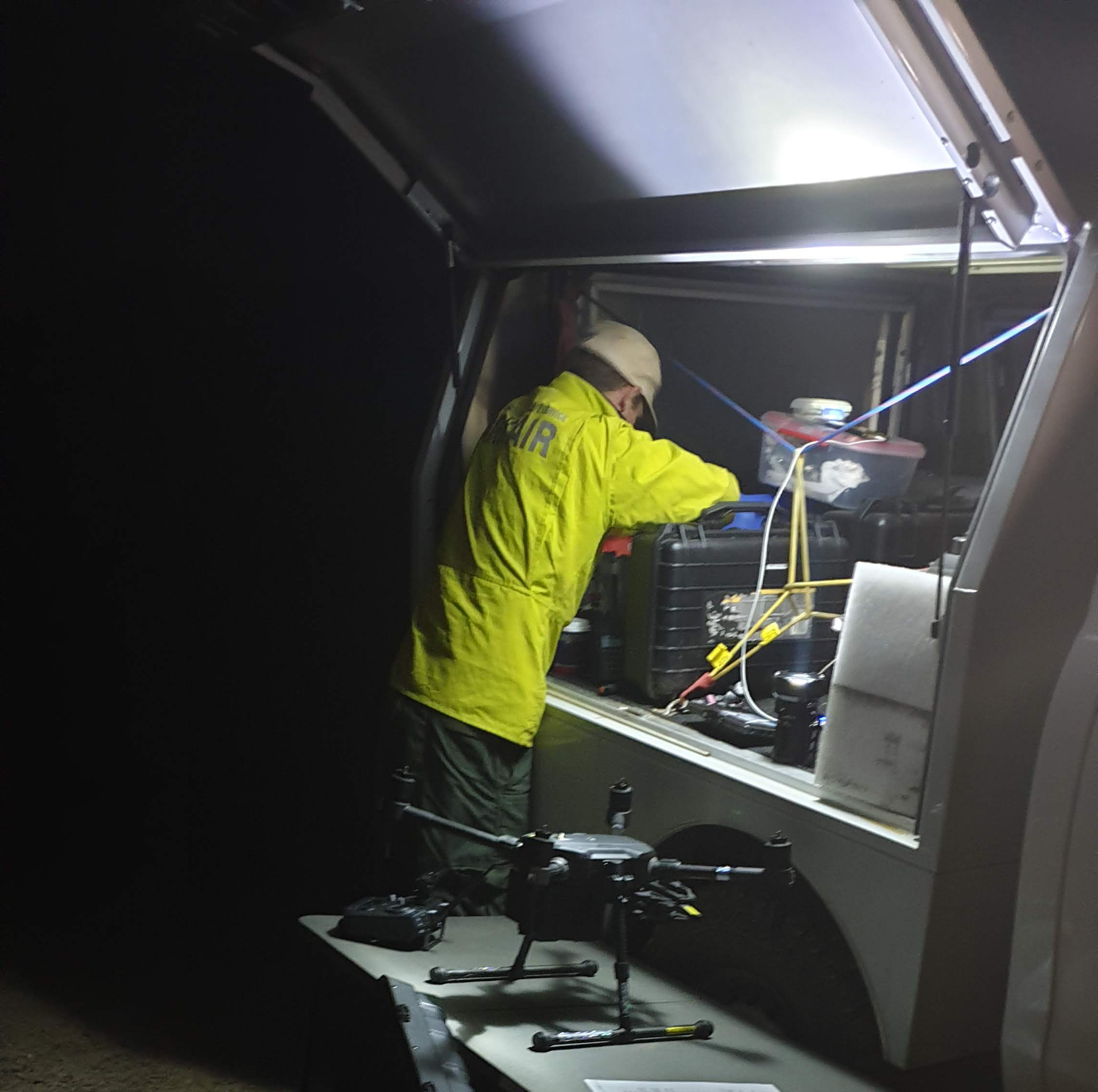 NSW National Parks Drone pilot setting up a drone under light from his vehicle at night. Photo: Scott Colefax / DCCEEW  © Scott Colefax