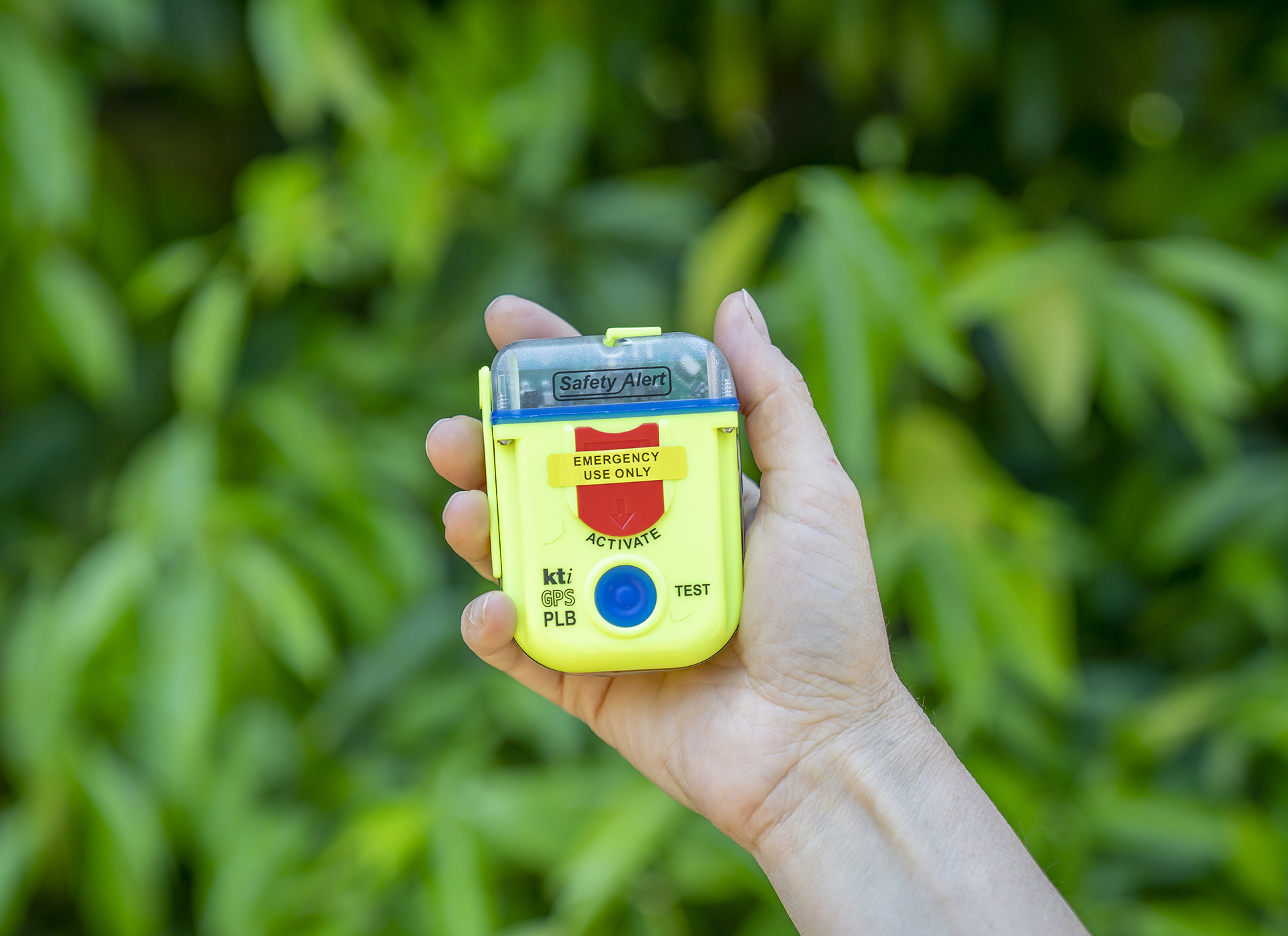 A close up of a hand holding a Personal Location Beacon. Photo: John Spencer