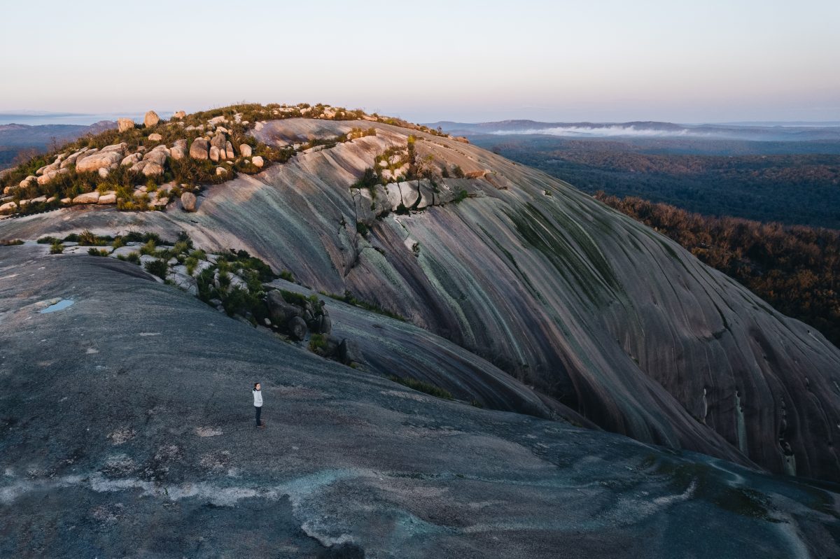 Aerial shot of a person standing on summit of Bald Rock, Bald Rock National Park. Photo credit: Harrison Candlin / DPE