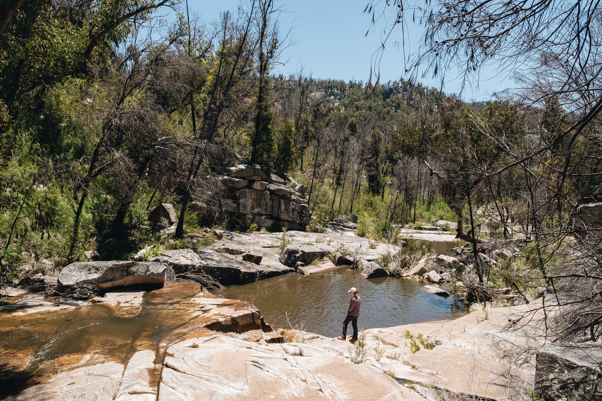 A person taking a moment at one of the lower pools on the Ugly Corner falls walking track. Photo credit: Harrison Candlin / DPE