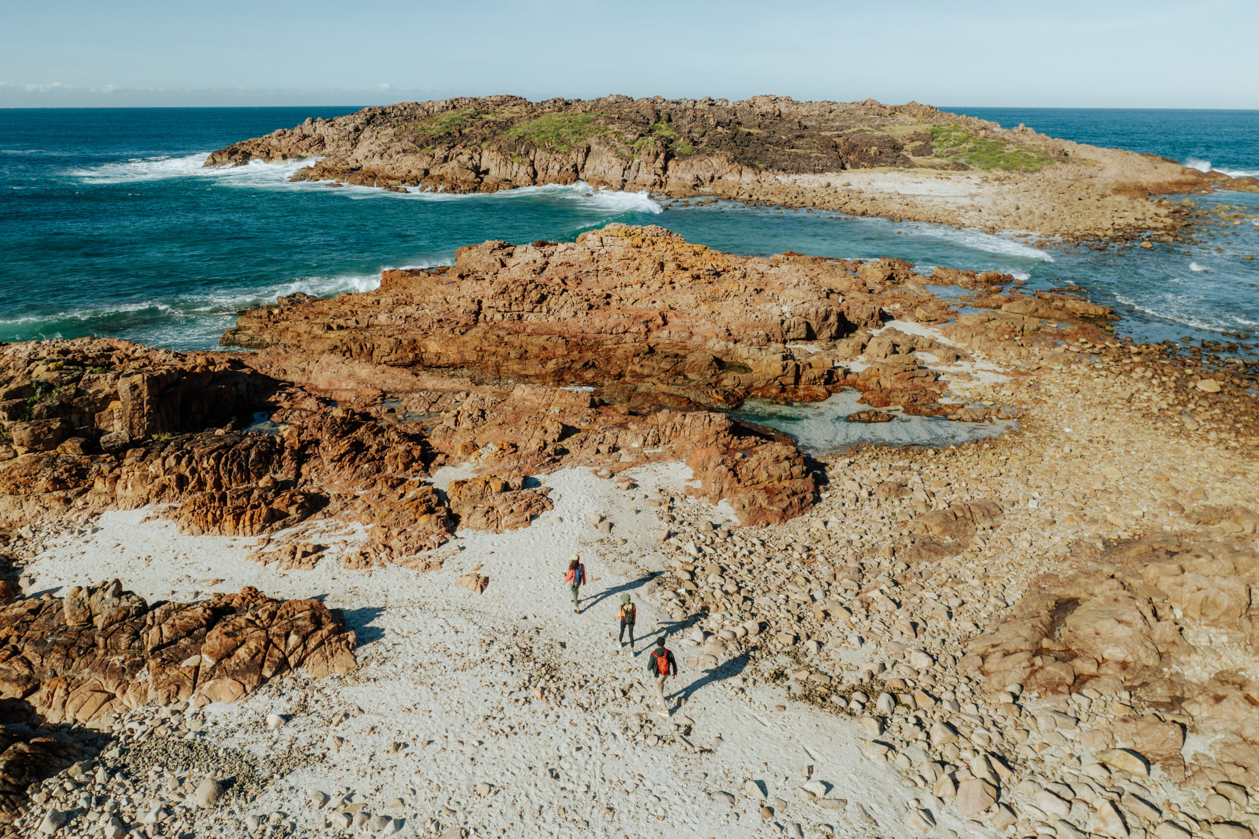 Aerial view of three people walking Tomaree Coastal Walk, Tomaree National Park. Photo: Remy Brand / DCCEEW © Studio Bilby