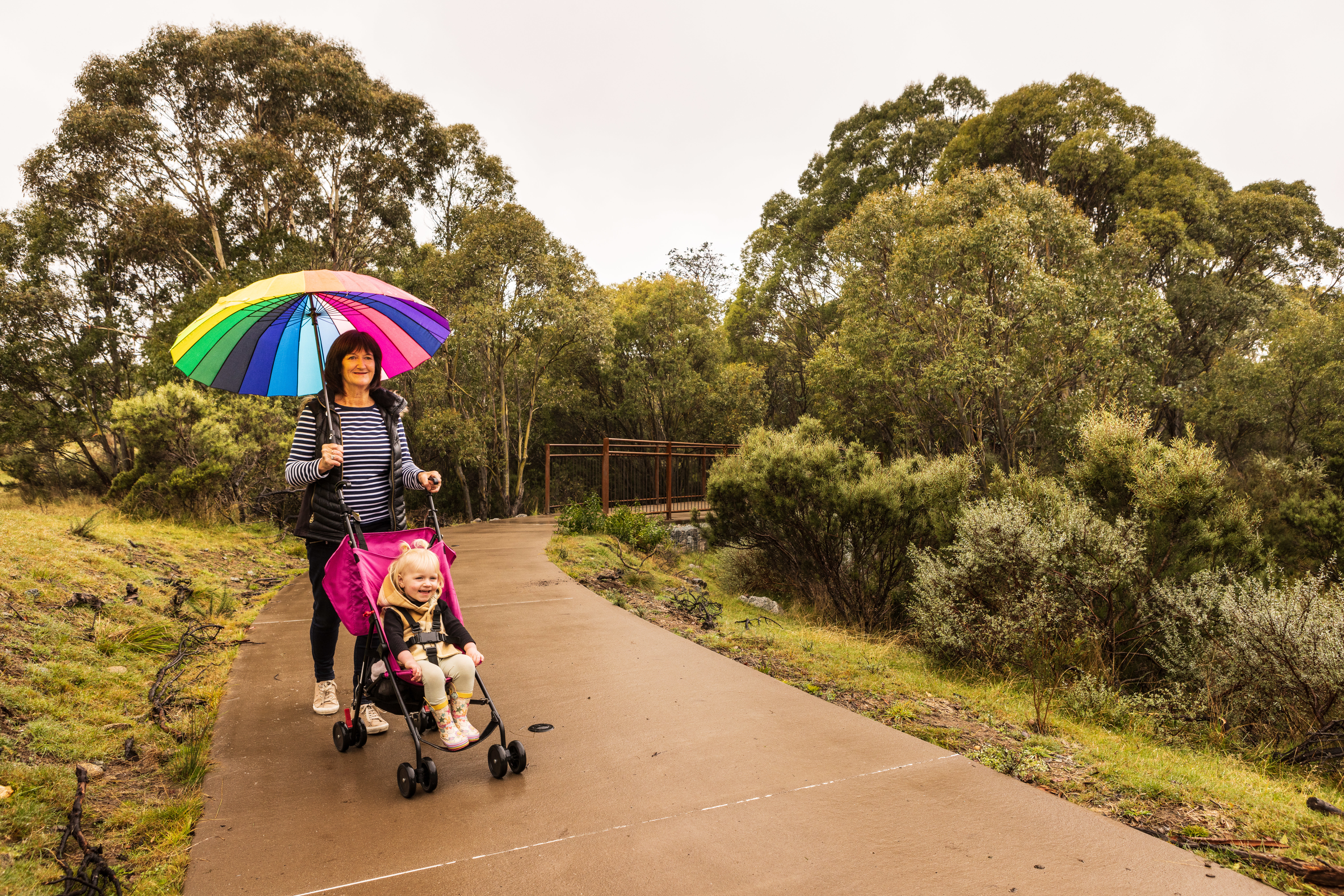 A person pushing a child in a pram on Bundilla accessible track. Photo credit: Murray Vanderveer / DPE