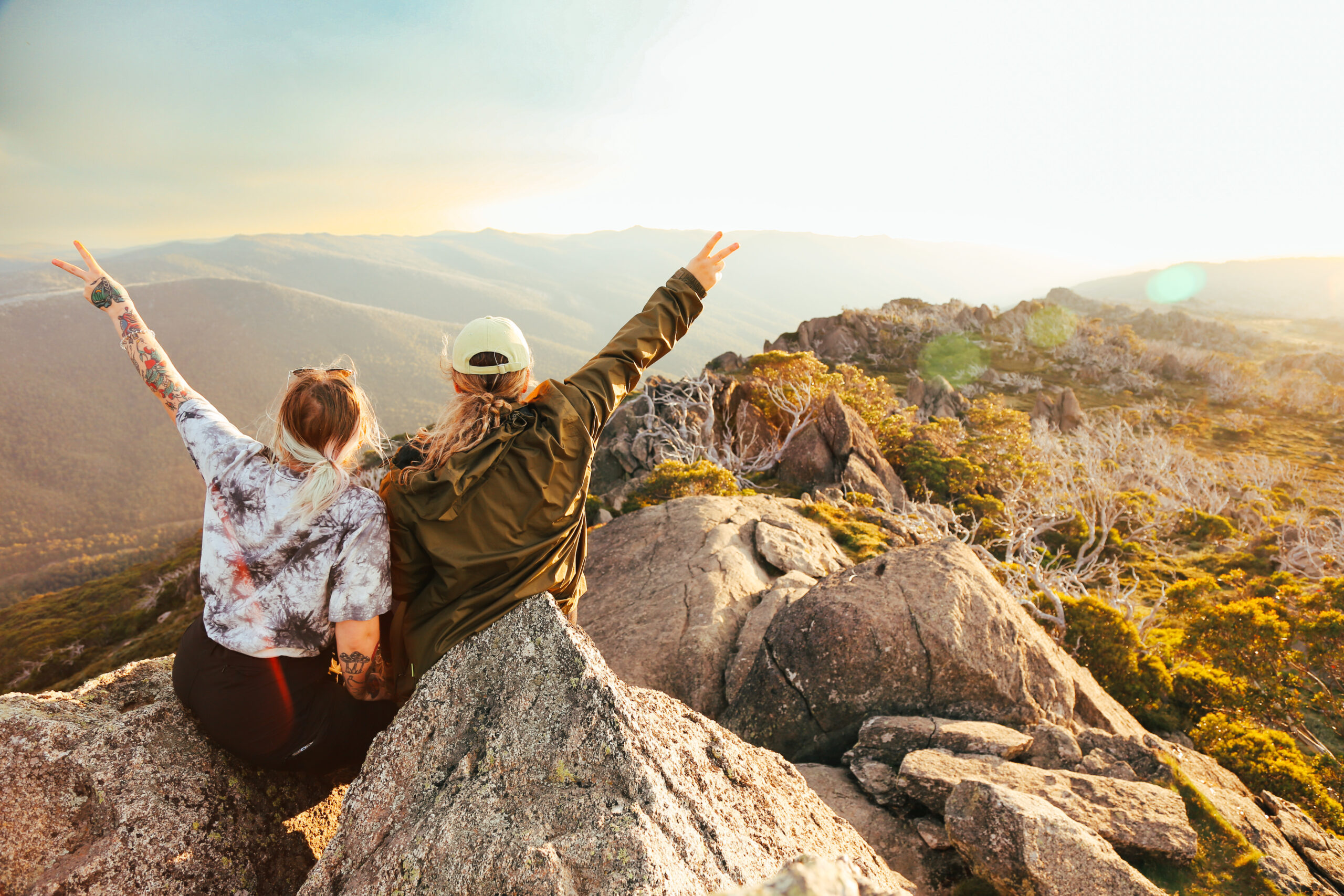 Two people holding up peace signs in Kosciuszko National Park. Photo credit: Ashley Hunter / DPE