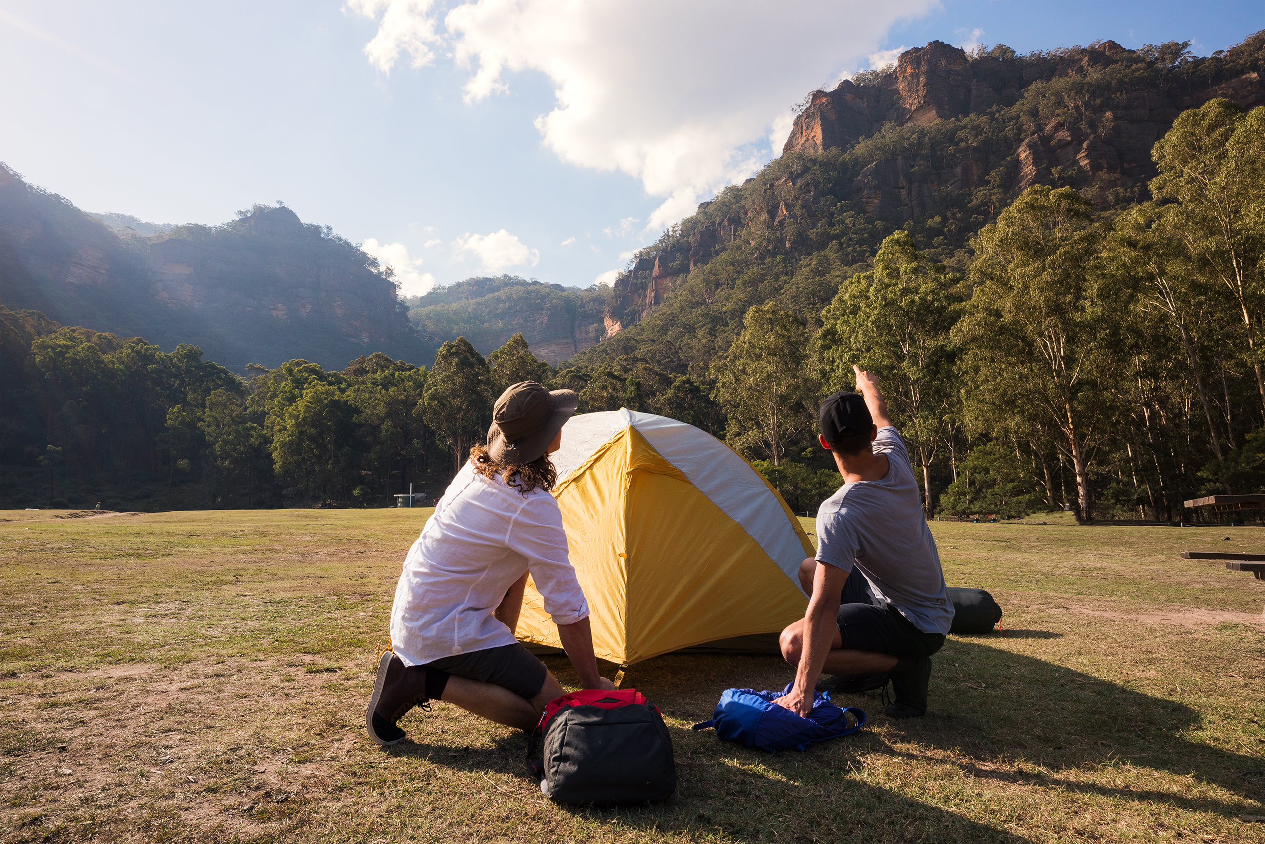 Two people outside a tent in Newnes Campground - walk in, looking up at the cliffs, Wollemi National Park. Photo credit: Daniel Tran / DPE