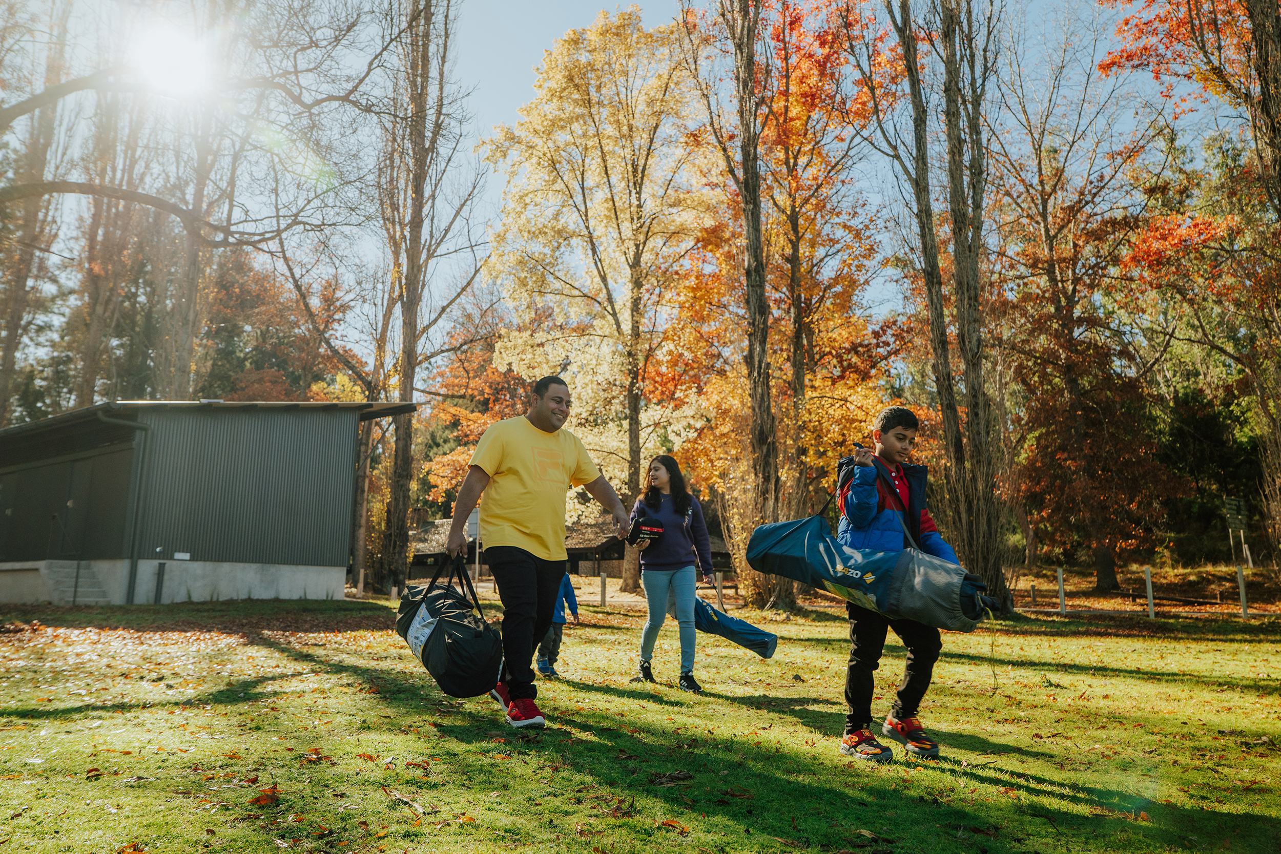 A family of four carrying their camping gear to Wombeyan Caves Campground, Wombeyan Caves. Photo Credit: Remy bRand / DCCEEW
