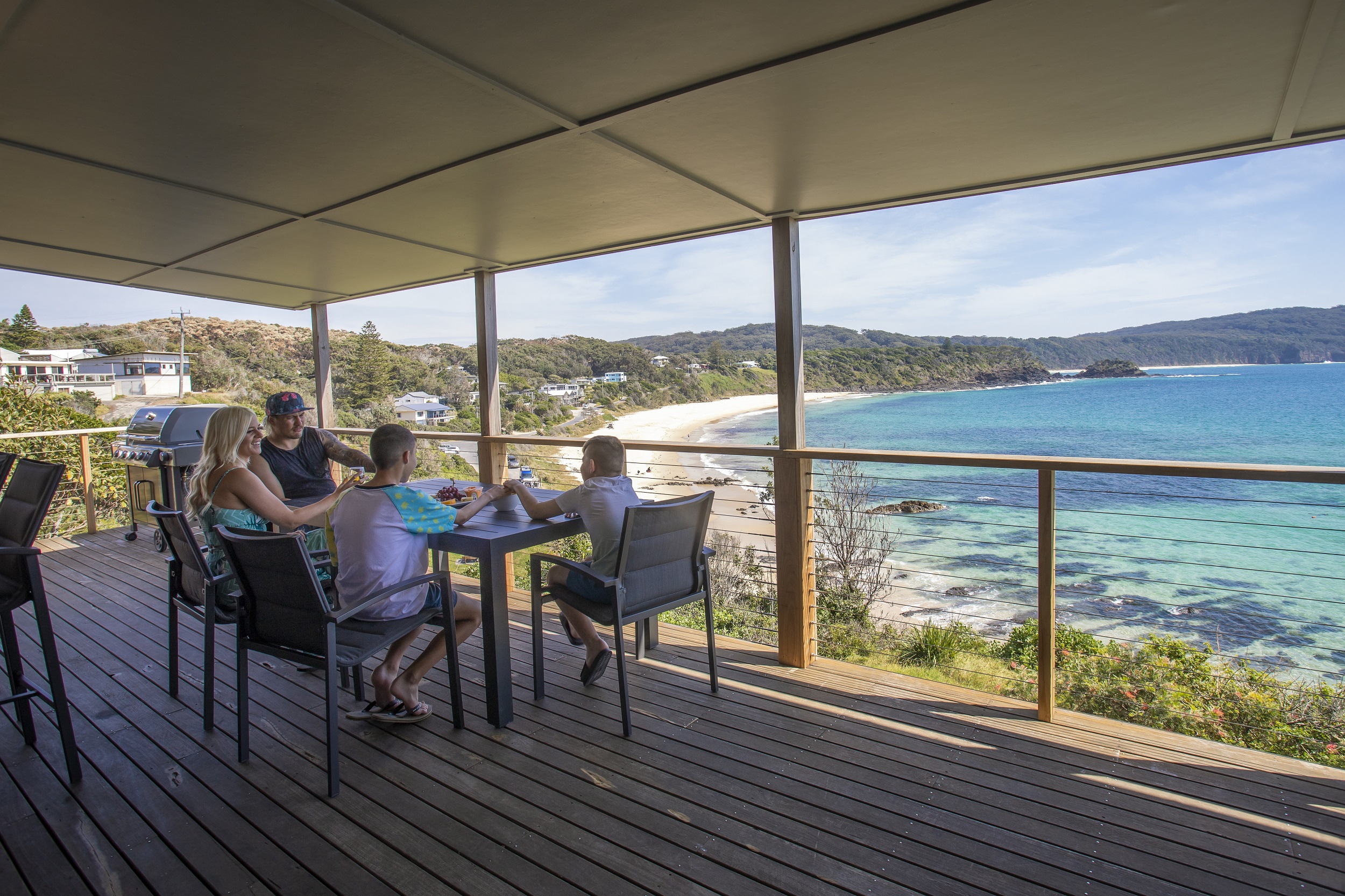A family enjoys a meal on the deck at Davies Cottage. Photo credit: Brent Mail/DCCEEW