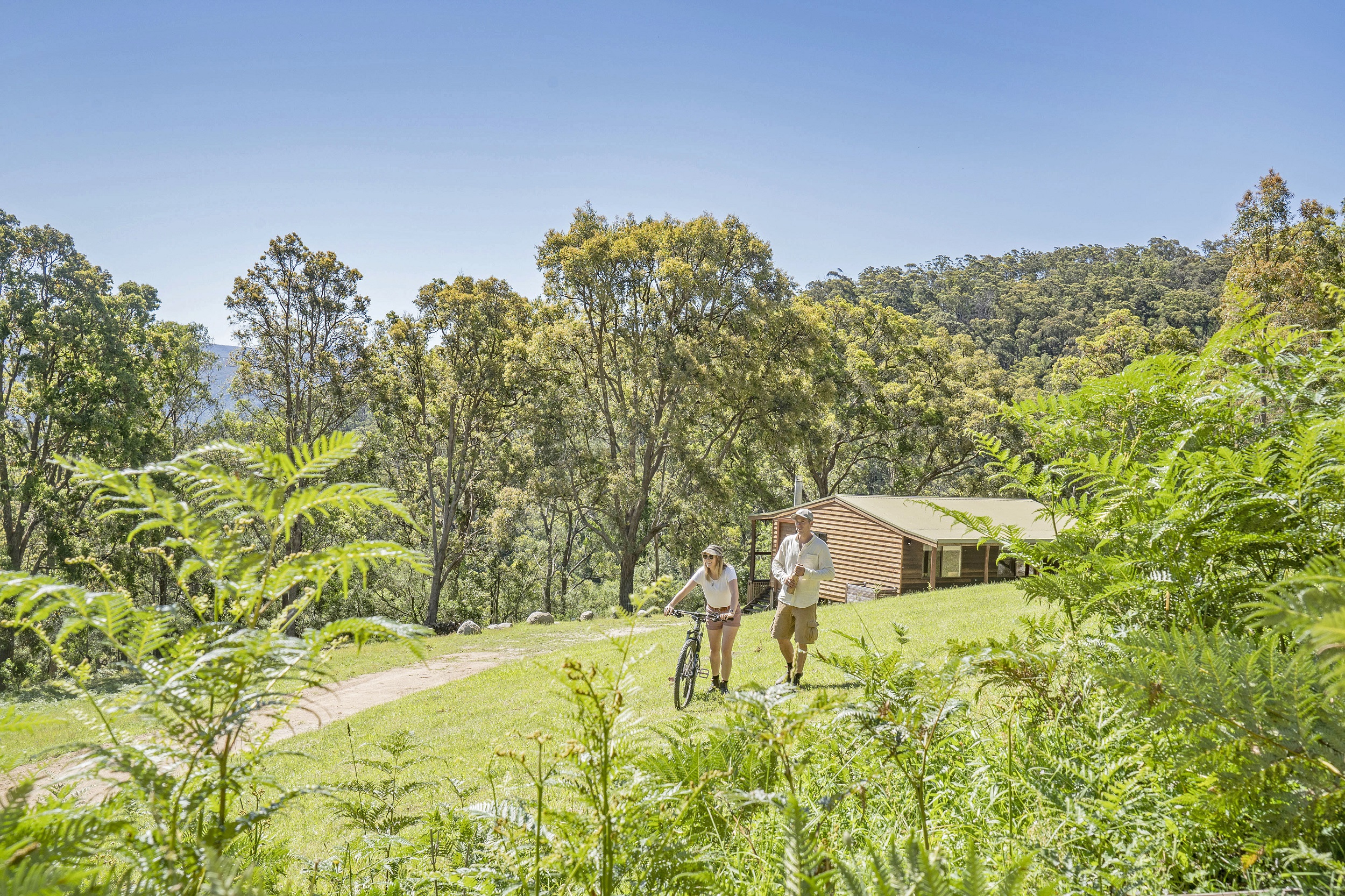 A couple with push bike outside Galong Cabins. Photo credit: Simone Cottrell/DCCEEW
