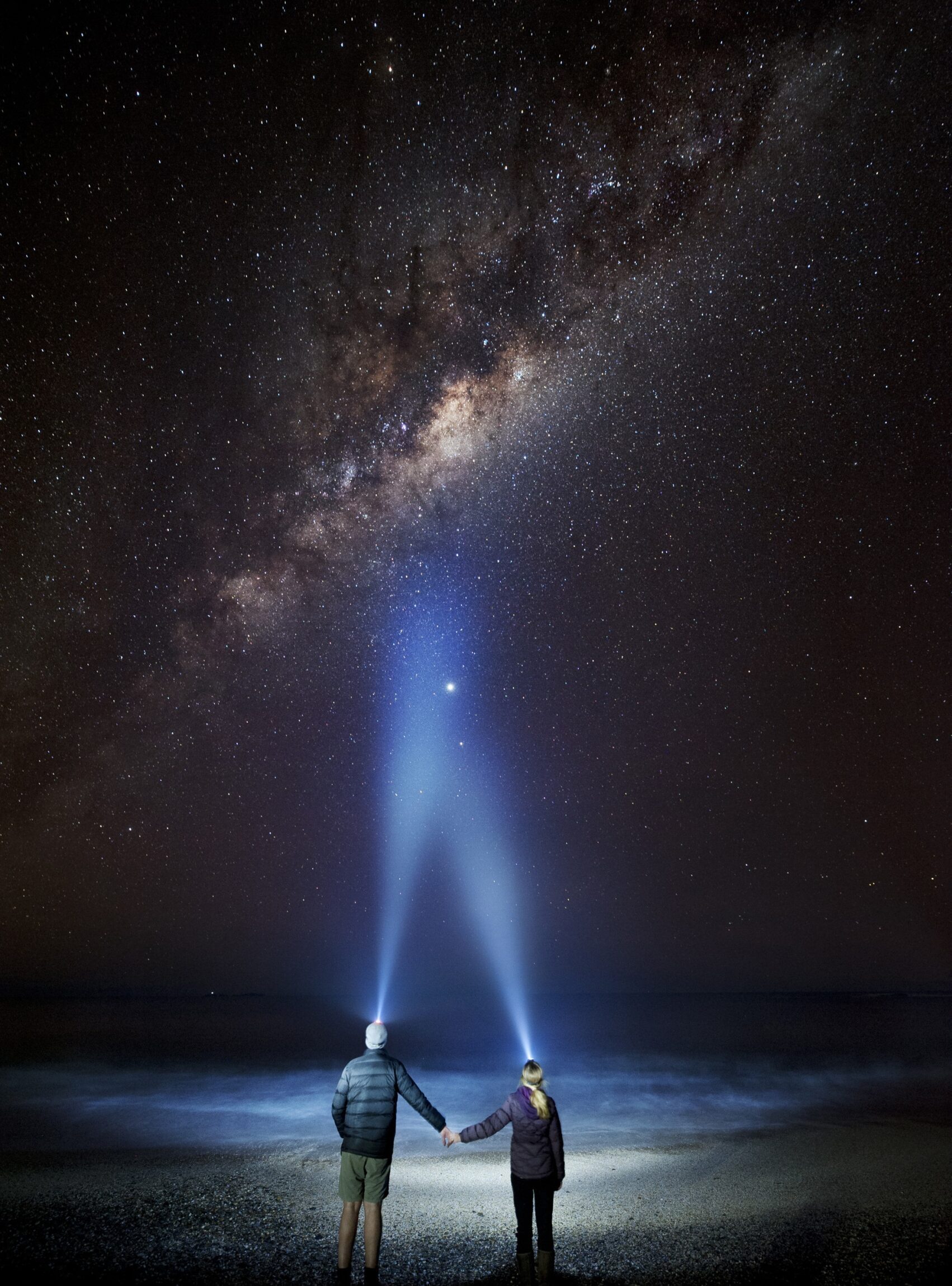 Two people with head torches looking up into the night sky at Yuraygir National Park. Photo credit: Lisa Russo/DCCEEW