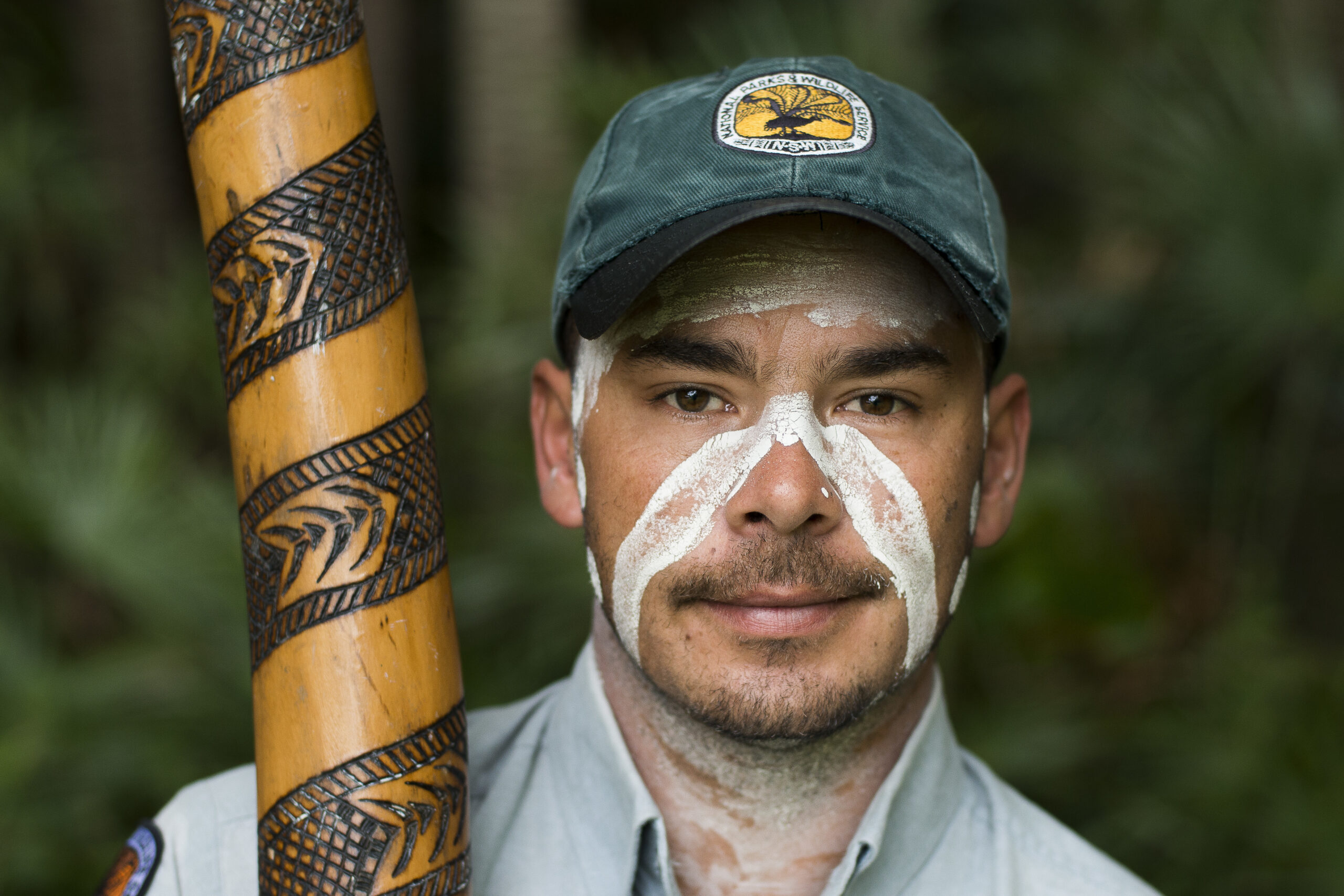 Nigel Stewart, an Aboriginal education guide with painted face and didjeridoo. Photo credit: Aristo Risi/DCCEEW