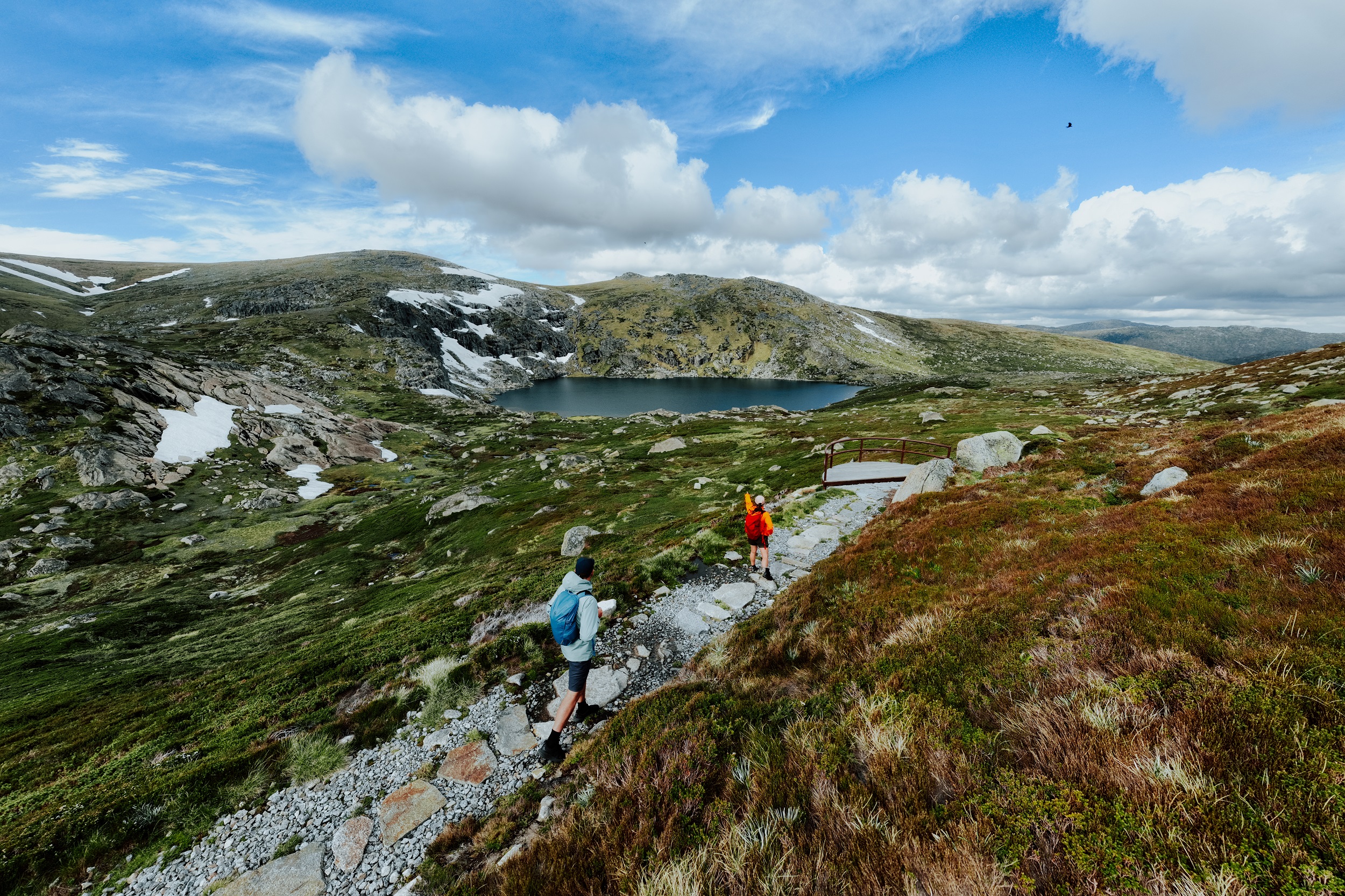 Two walkers take in the veiw from Blue Lake lookout on the Snowies Alpine Walk. Photo credit: Daniel Parsons/DCCEEW © Studio Bilby