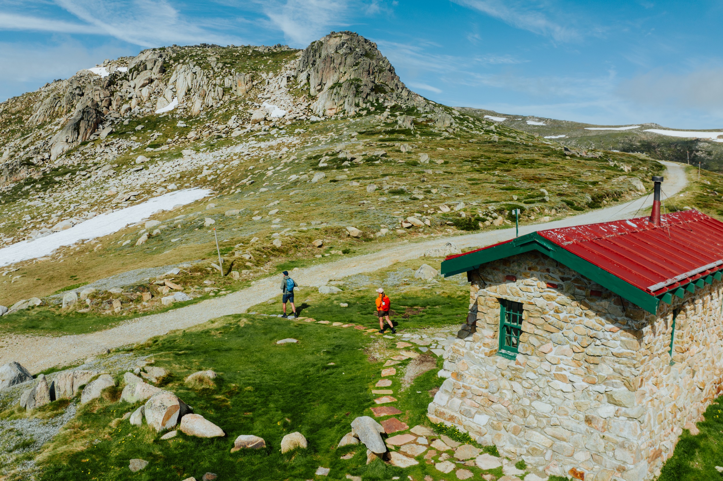 Two people walking past Seamans Hut on the Snowies Alpine Walk. Photo credit: Daniel Parsons/DCCEEW © Studio Bilby