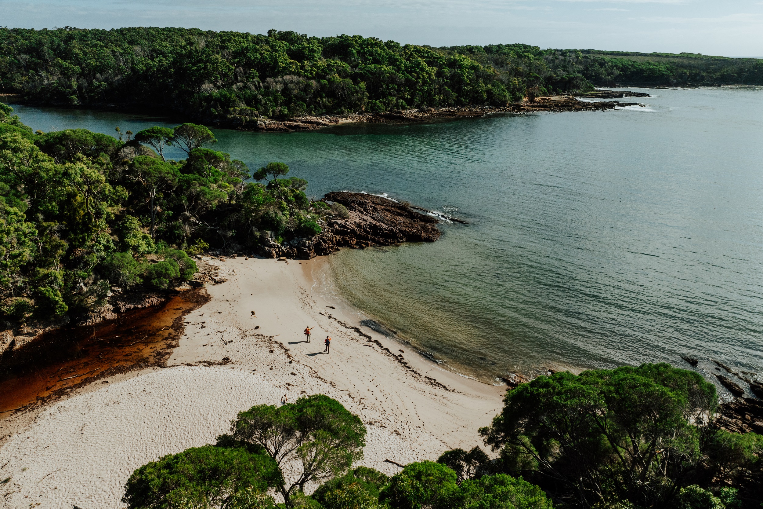 Two walkers at Bittangabee Bay on the Light to Light Walk. Photo credit: Daniel Parsons/DCCEEW © Studio Bilby
