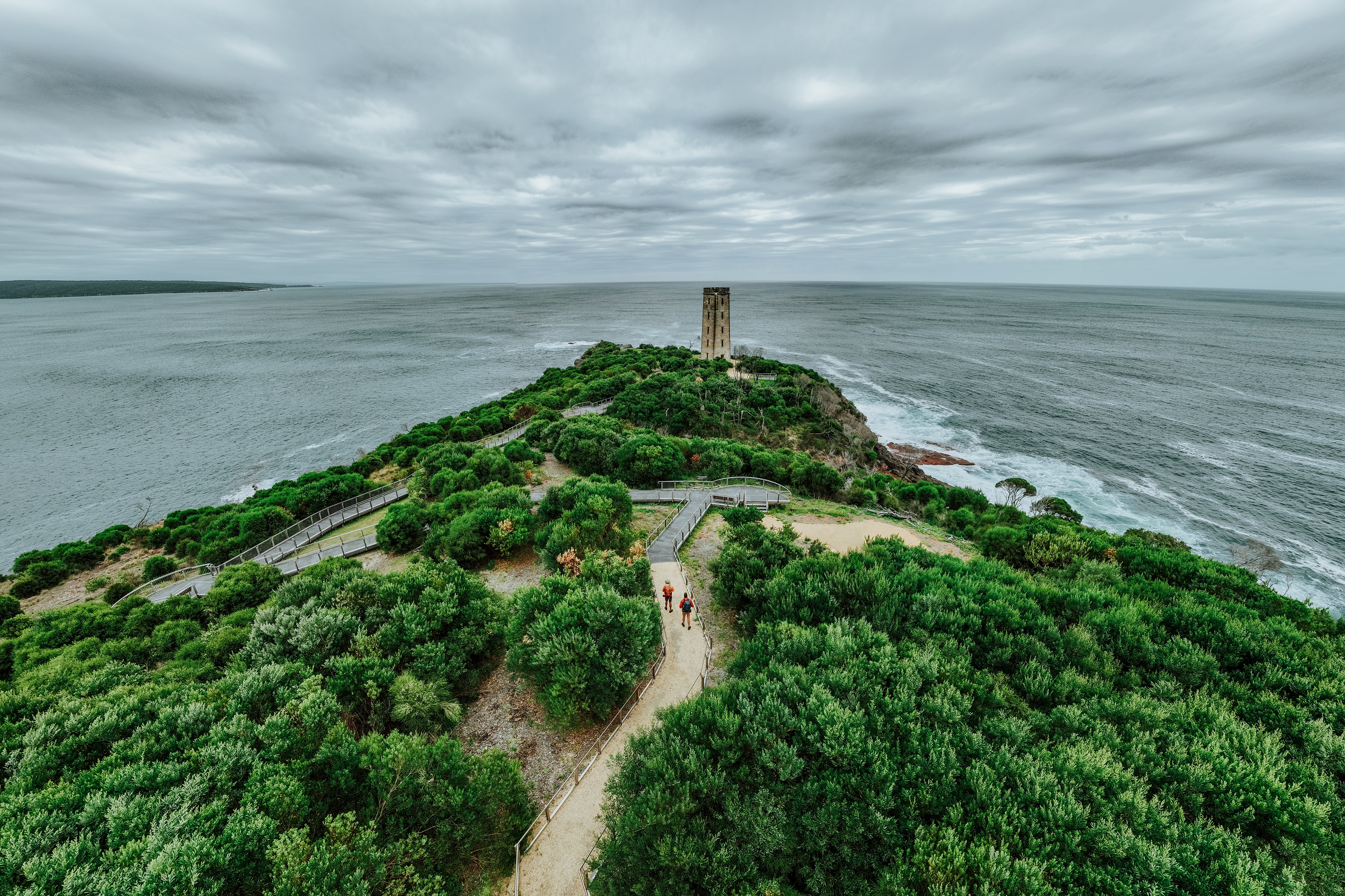 Two walkers at Boyds Tower on the Light to Light Walk. Photo: Daniel Parsons / DCCEEW © Studio Bilby