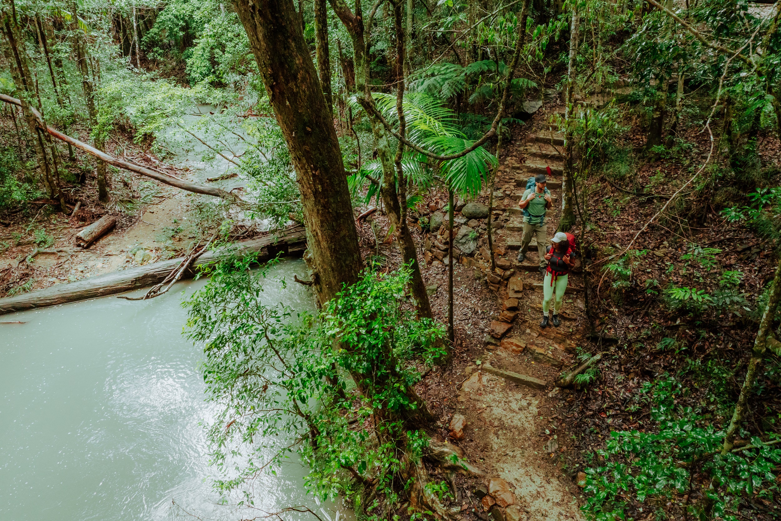 Two hikers descending stairs to the base of Unicorn Falls on Gidjuum Gulganyi Walk. Photo: Daniel Parsons/DCCEEW © Studio Bilby