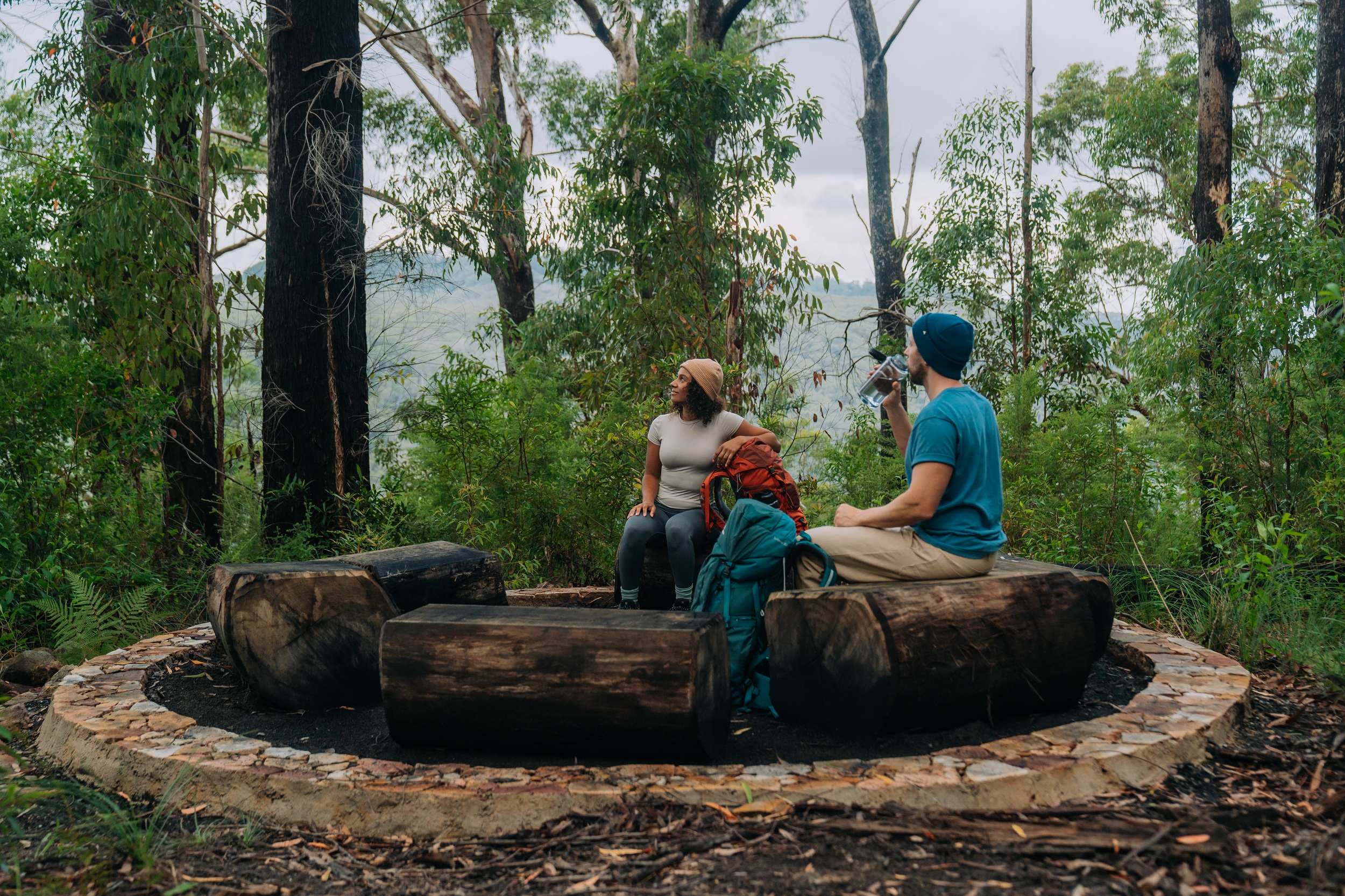 Two hikers sit in a yarning circle at Weeun Weeun campground on Gidjuum Gulganyi Walk. Photo: Remy Brand/DCCEEW © Studio Bilby