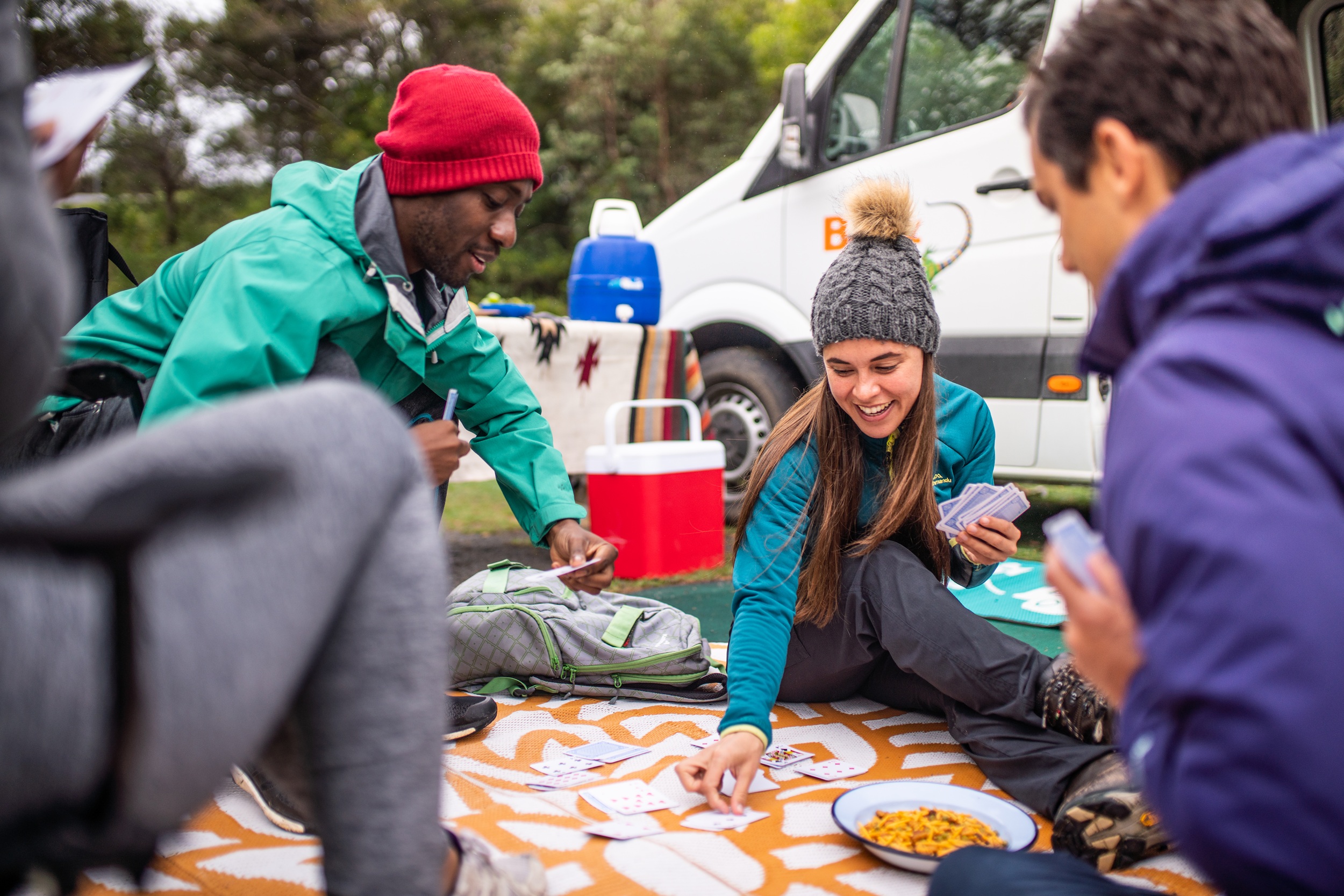 A group of friends playing cards at their campsite.