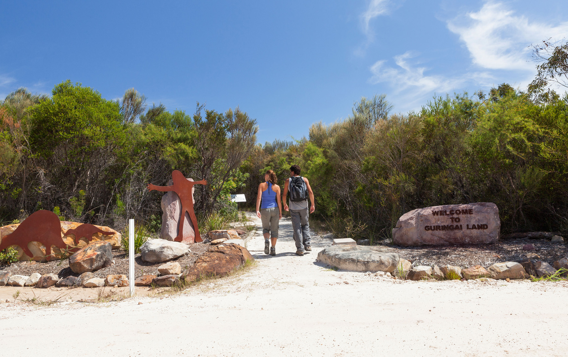 Two people walking to look at aboriginal rock engravings at Ku-ring-gai Chase National Park. Photo: David Finnegan / DCCEEW © David Finnegan
