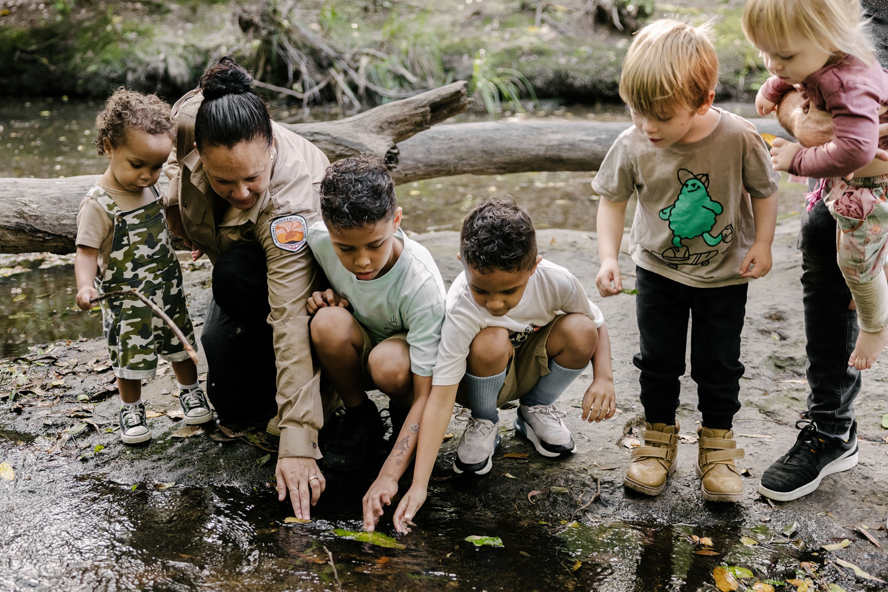 Aboriginal Discovery Ranger with children on a tour in Glenrock State Conservation Area. Photo: Zain Kruyer ©  Zain Kruyer / DCCEEW
