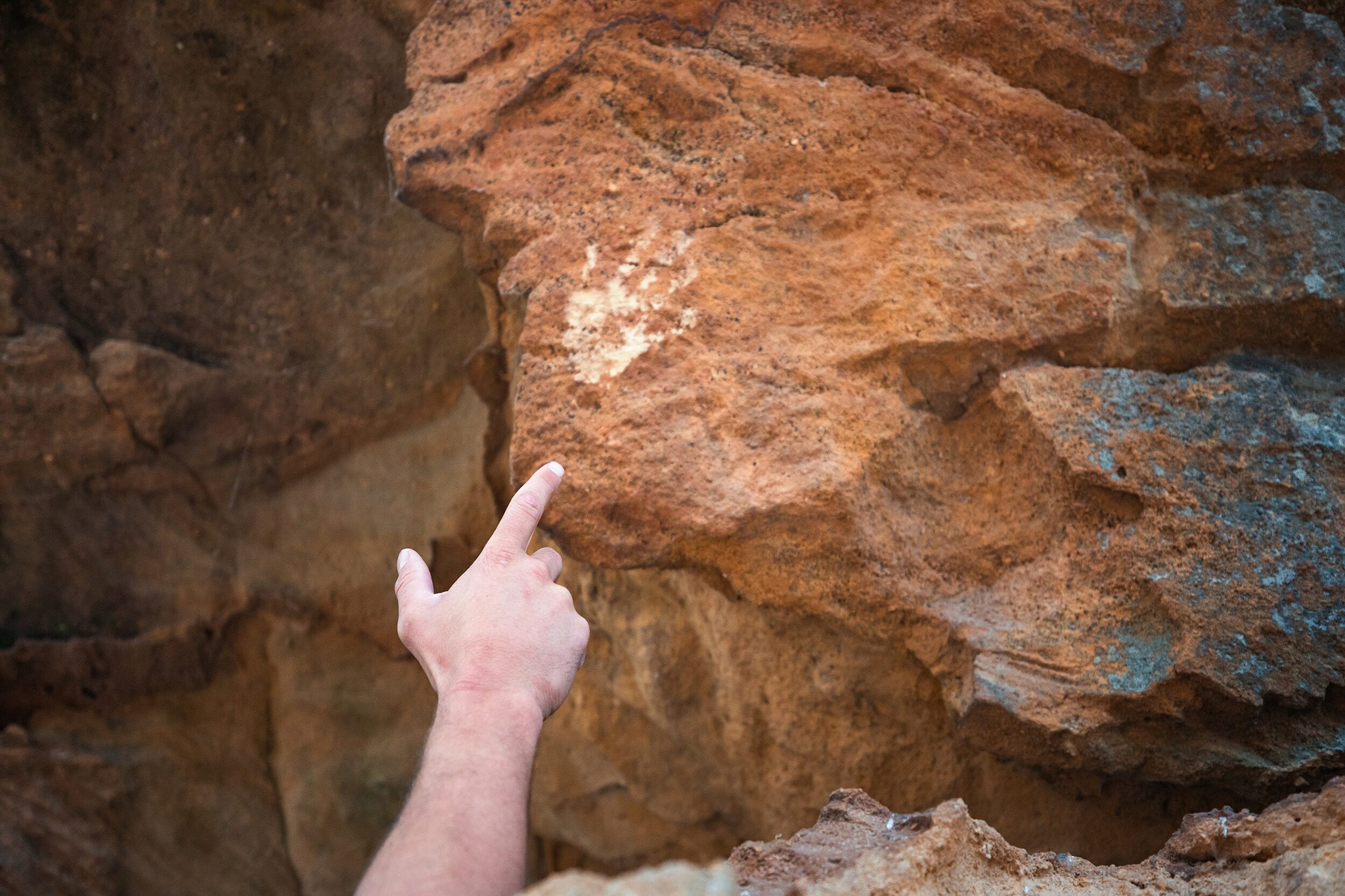 Hand points to Aboriginal artwork in Wollemi National Park. Photo: Daniel Tran / DCCEEW © Studio Bilby