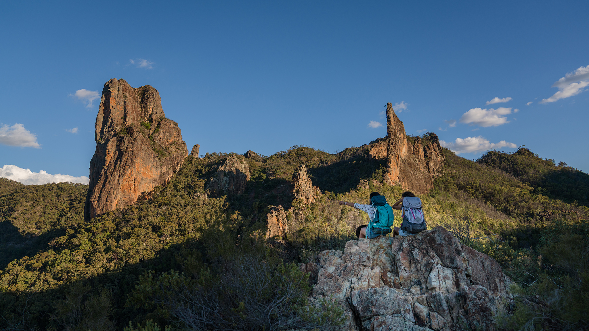 Two people sitting at enjoying the view from Breadknife and Grand High Tops Walk. Warrumbungles National Park. Photo: Rob Mulally / DCCEEW © Studio Bilby