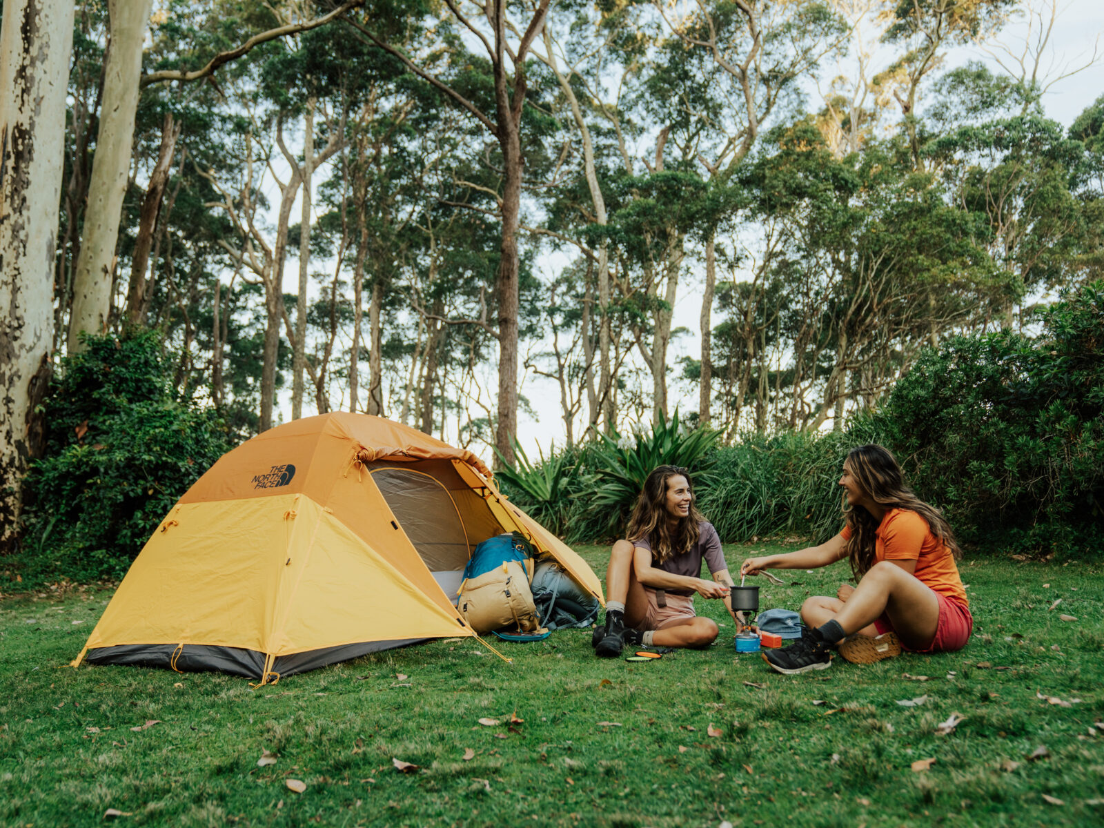 2 campers making coffee outside their tent at Depot Beach campground, Murramarang National Park. Photo: Remy Brand/DCCEEW © Studio Bilby