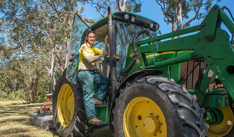 A field officer on a tractor doing maintenance work in Tomaree National Park. Credit: John Spencer © DCCEEW
