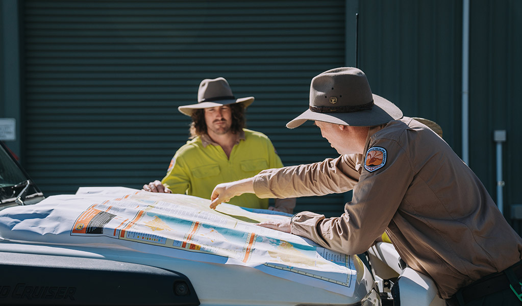 2 NPWS Rangers looking at a map. Credit: Remy Brand &copy; DCCEEW