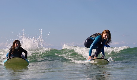Two girls surfing in an accessible surf therapy lesson with Ability Surf. Credit: Grace Althorpe &copy; Ability Surf