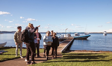 People on a Coast XP tour looking out over a pier and boats on Lake Macquarie. Credit &copy; CoastXP
