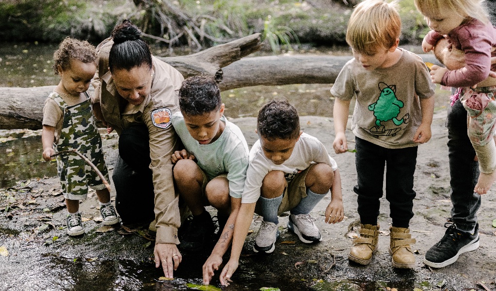 Children and an Aboriginal Discovery Ranger looking into a creek in Glenrock State Conservation Area. Credit and &copy; Zain Kruyer