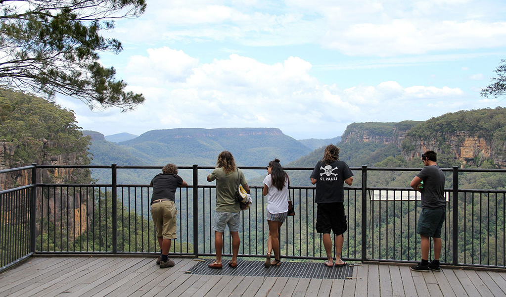 People enjoying the view at Fitzroy Falls lookout over Yarrunga Valley, Morton National Park. Credit: John Yurasek/DCCEEW &copy; OEH