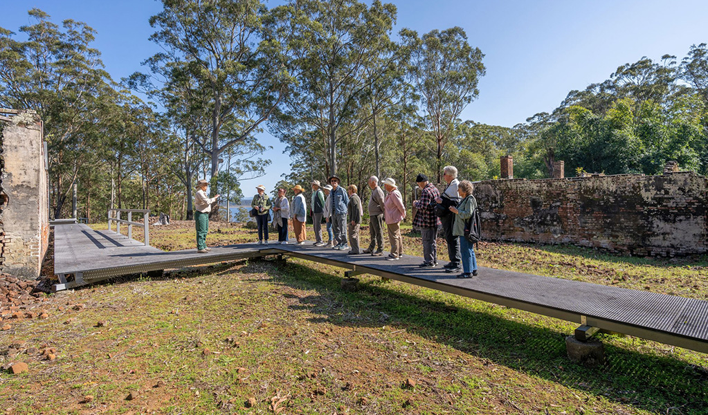 Tour group listening to a guide on a raised platform at Innes Ruins Historic Site. Credit: John Spencer &copy; DCCEEW