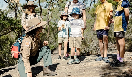 A Discovery ranger showing a group of kids through the bush on a guided tour. Credit &copy; Zain Kruyer/DCCEEW